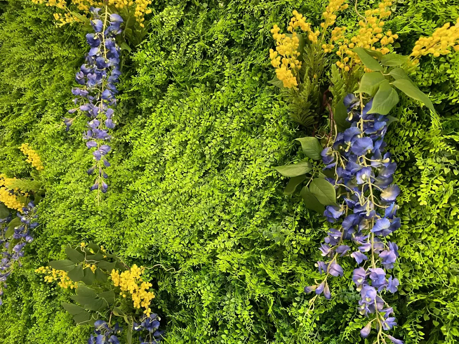 Detail der künstlichen Pflanzenwand mit grünen und violetten Akzenten